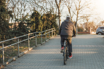 Man Riding Bicycle Down Brick Walkway in a Park
