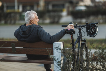 Man With Bicycle Taking a Coffee Break on a Bench