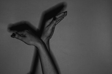 Female hands gesturing in the form of a bird on a light background in the dark under the light of a...