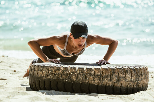 Woman Doing Push Ups on Tire on Beach