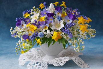 Bouquet of wild spring flowers in a cup, blue muscari, hepatica, pansies, yellow anemones, white bird cherry. Beautiful card - 793218212