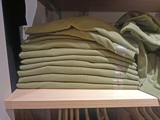 A stack of green clothes is on a shelf in a supermarket