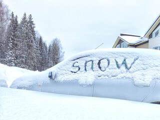 The car is covered with snow and the inscription snow on the glass. Extreme snowfall, severe...