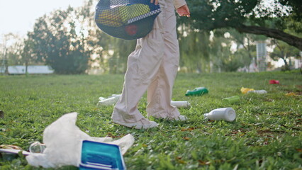 Woman walking polluted grass at park holding eco-friendly bag closeup. Girl feet