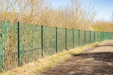 green Palisade security Fencing against a bright blue sky