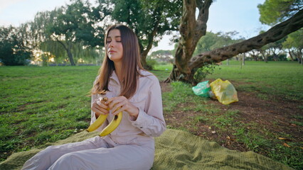 Picnic woman holding banana relaxing on park blanket closeup. Smiling young lady