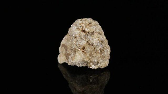 Polished mineral stone albite rotates in a circle on a black background