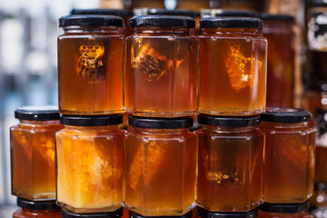 Close up. Honey in glass jars, with a piece of honeycomb inside.