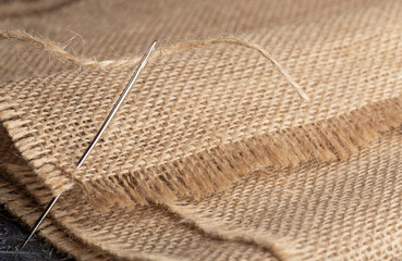 burlap, wooden button and sewing needle close up