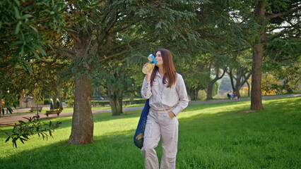 Drinking girl enjoy park leisure standing green grass with water bottle closeup