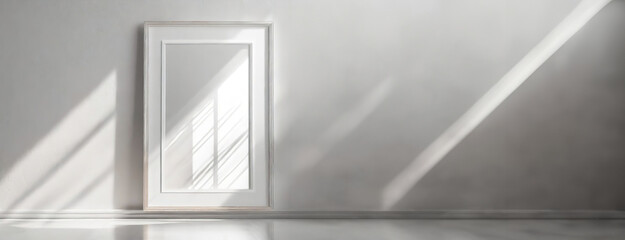 Empty picture frame on a white wall with soft shadows. The blank frame suggests potential for artwork or photography display, simplicity reigning in the composition.