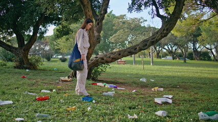 Volunteer collecting park trash. Eco-active girl cleaning green nature space