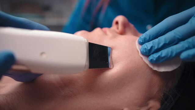 Caucasian woman receiving ultrasonic facial peeling in a beauty salon. Cleaning the face with an ultrasonic scraper. Cosmetology and facial skin care. Facial care.