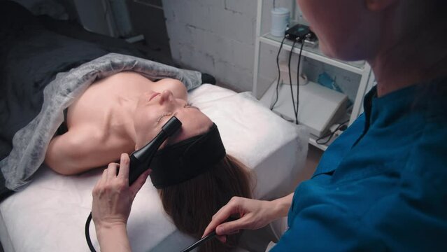 Lymphatic drainage massage is a hardware process. A cosmetologist-therapist gives a woman a rejuvenating facial and neck massage in a spa salon. Beauty and body care concept