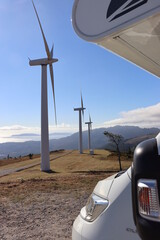 Close-up of a motorhome stopped on top of Mount Pindo (Carnota, Galicia, Spain) with the windmills in the background. Upright image.
