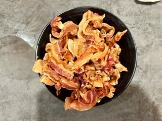 A bowl of bacon strips is on a table