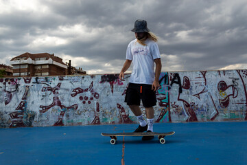 A man in a white shirt and black shorts is skateboarding on a blue surface