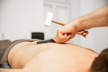 Masseur nutzt einen therapeutischen Hammer zur Massage / Masseur uses a therapeutic hammer for...