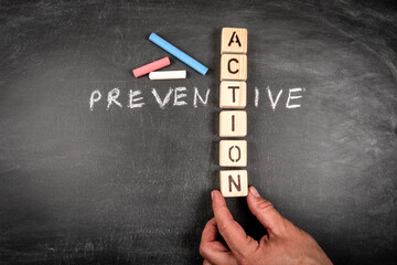 Preventive Action. Wooden block crossword puzzle and pieces of chalk on a chalkboard background - 793269008