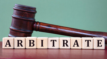 ARBITRATE - word on wooden cubes on background of judge's gavel