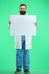 A male doctor, full-length, on a green background, shows a white sheet