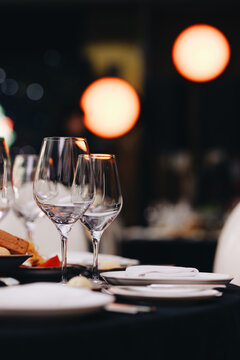 Beautifully organized event - round served table banquet ready for guests, round decorated table with empty plate, glasses, forks, napkin. Elegant dinner table 