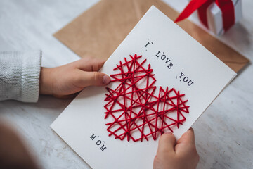Little kid preparing diy handmade cute post card for Mother's Day with a message I love you mom....