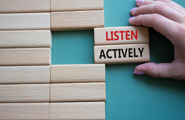 Listen actively symbol. Wooden blocks with words Listen actively. Businessman hand. Beautiful grey...