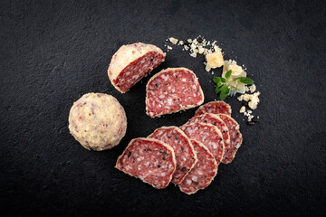 Traditional Italian saltufo salami with parmesan coated and truffle served as top view on a black design tray