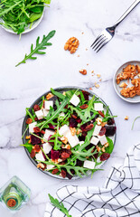 Beetroot and white cheese salad with arugula, lettuce, chard and walnuts, white table, copy space. Fresh useful vegetarian dish for healthy eating - 793287445