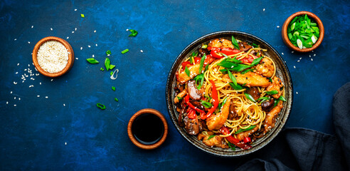 Hot stir fry egg noodles with turkey, paprika, mushrooms, chives and sesame seeds with ginger, garlic and soy sauce. Asian cuisine dish. Blue table background, top view banner - 793287453