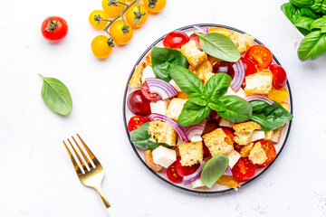 Fresh summer salad with tomatoes, stale bread, onion, cheese, green basil and olive oil, white table background, top view - 793287865