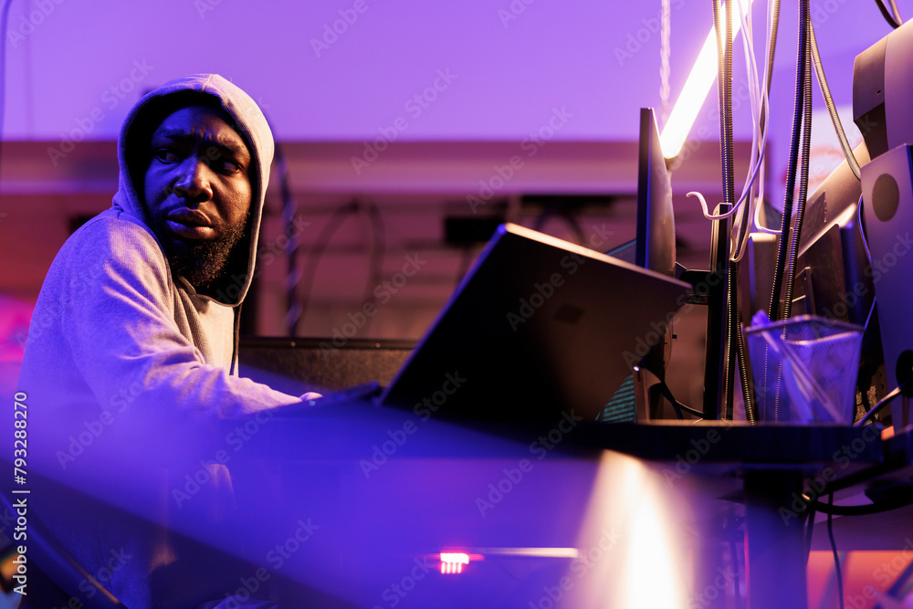 Poster concerned hacker looking over shoulder, afraid of cyber police while doing cyberattack. scared afric