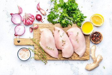 Raw chicken breast fillet on wooden cutting board, white table background, top view - 793288257