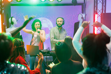 Young man and woman band performing on stage in nightclub at techno music festival. People partying...