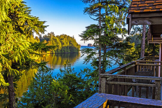 View of a bay surrounded by horse trees from the balcony of a cottage, West Coast of Vancouver Island near Ucluelet. Calm water, rocky island in the distance