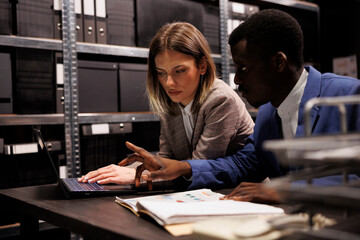 Investigators working late at night in arhive room, analyzing criminal case evidence searching for...