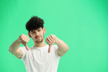 A man, on a green background, in close-up, shows his finger down