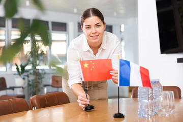Employee of delegation prepares negotiating table - sets up the flag of China and France