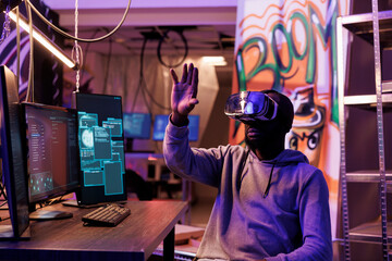 Hacker wearing vr glasses and getting unauthorized illegal access while exploring metaverse. African american criminal using virtual reality helmet to navigate database while breaking law