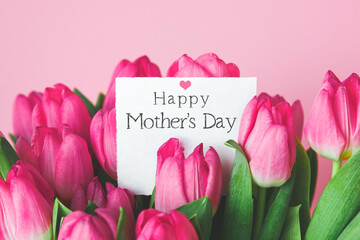 beautiful bright bouquet of pink tulips with a gift card with the text inscription Happy Mother's Day and pink heart, sweet wish concept - obrazy, fototapety, plakaty