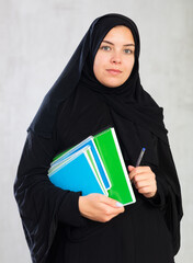 focused student girl with stack of large multicolored notebooks. Education in high school...