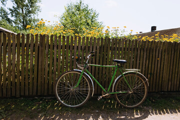 An old bicycle is placed on a wooden fence. bicycle on the background of yellow flowers