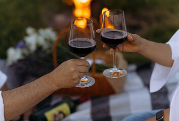 Young couple near the bonfire with two glasses of red wine. a couple raises a glass of red wine