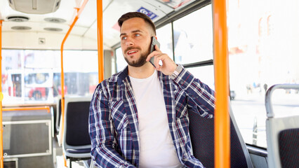 Young man riding in a city bus and talking on mobile phone