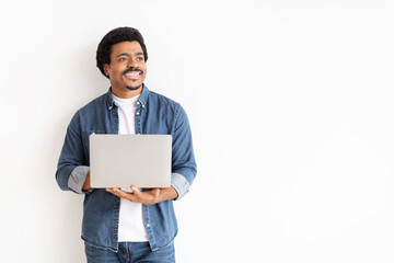Smiling man holding a laptop looking away