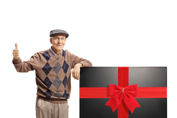 Elderly man leaning on a new flat lcd tv screen and gesturing thumbs up