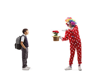 Surprised schoolboy watching a clown performing a trick with hat and flowers