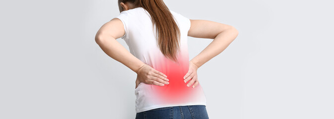 Young woman suffering from back pain on white background