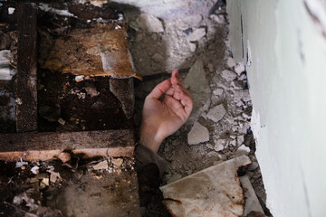 Human hand reaching out from under rubble